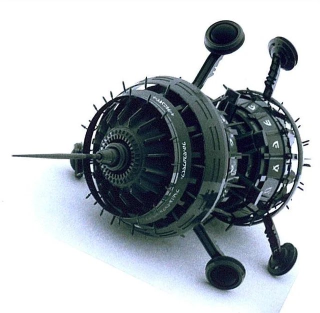 The CARET A1 object image: a dark green cylindrical device with round pads on three short arms, shown on a pale background.