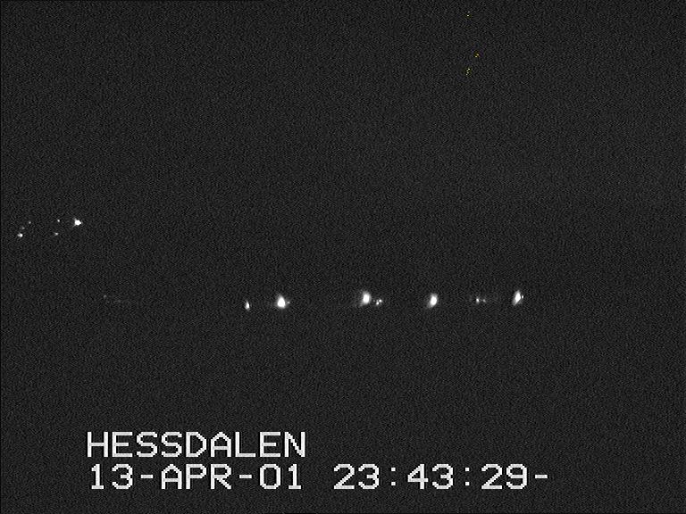 A black-and-white Hessdalen Automatic Measurement Station frame timestamped 13 April 2001, showing several lights over a dark valley.