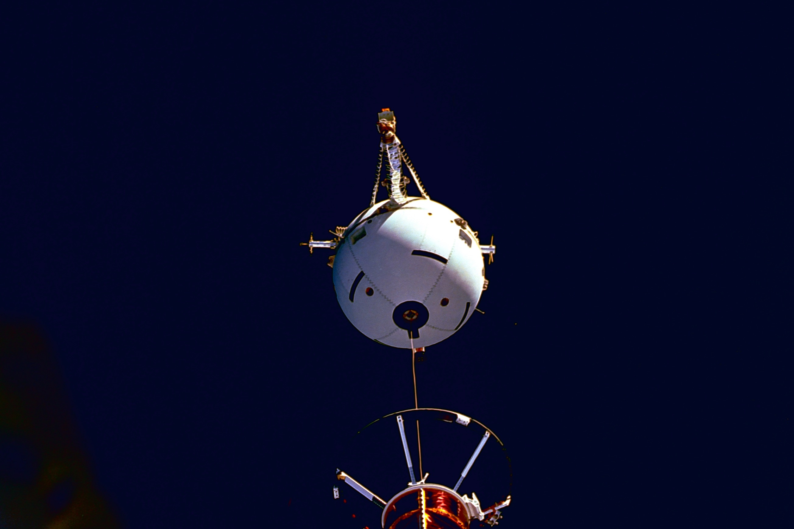 NASA photograph of the Tethered Satellite System during STS-75 deployment: a white spherical satellite hangs above the Space Shuttle Columbia payload bay against black space.