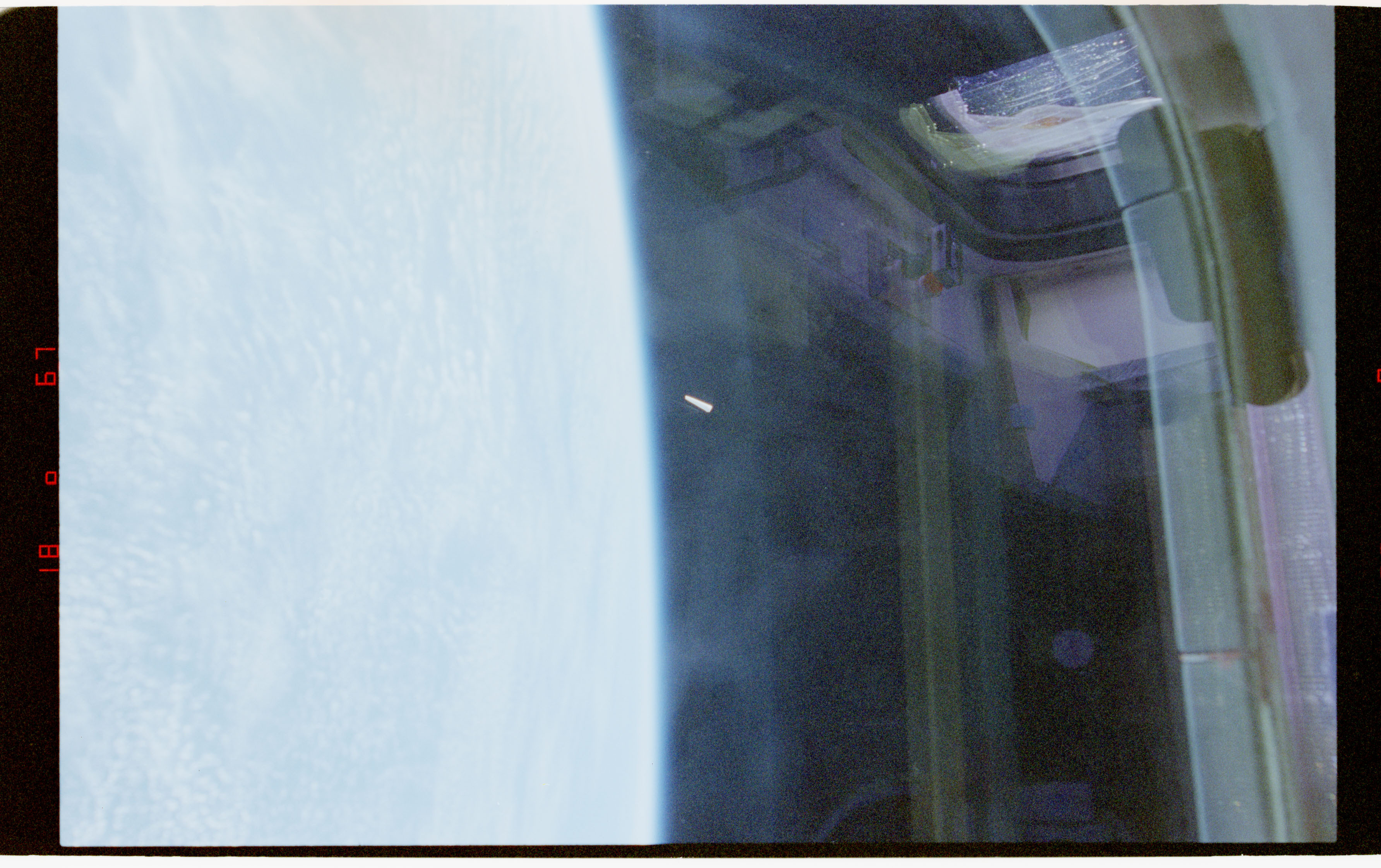 Official Release 04 image from STS-80: a small bright, elongated object appears against Earth and Columbia's payload-bay structure.