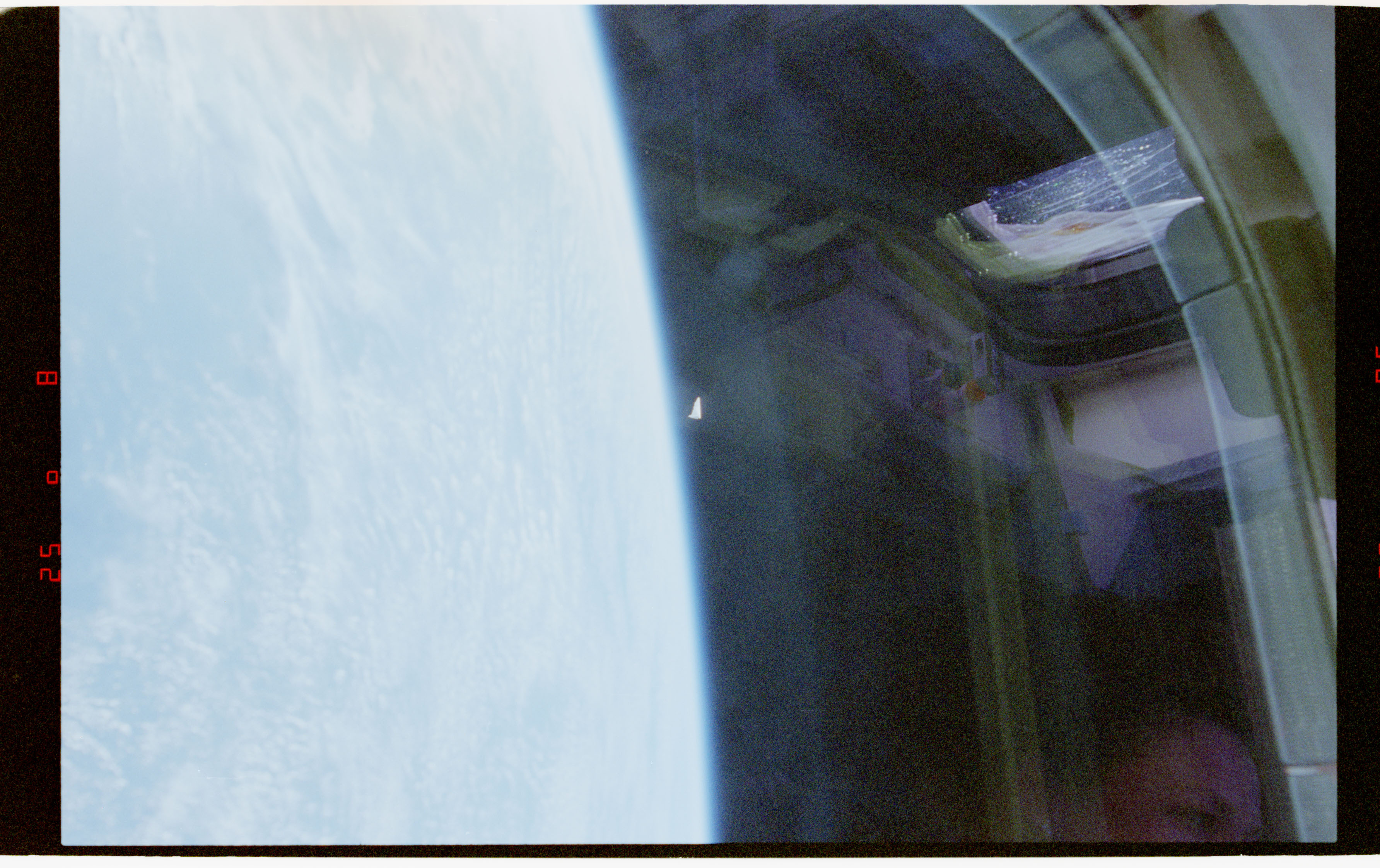 Release image D031: a small bright, compact mark appears beside Columbia's payload-bay structure and Earth.