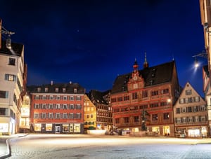 A line of Starlink satellites crossing a starry sky over Tübingen’s town hall at night.