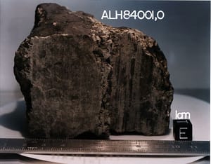 NASA photograph of the dark Martian meteorite ALH84001 with a scale ruler and specimen label.